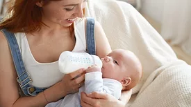 smiling mom feeding baby a bottle