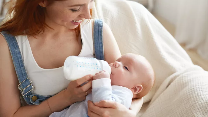 smiling mom feeding baby a bottle