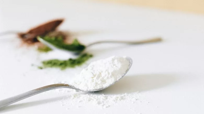 spoonfuls of powdered additives and ingredients in green, white, and brown