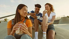 three people smiling and eating food outside