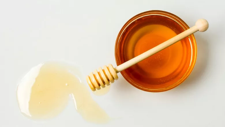 dish of honey, honey wand, and honey pooled on table