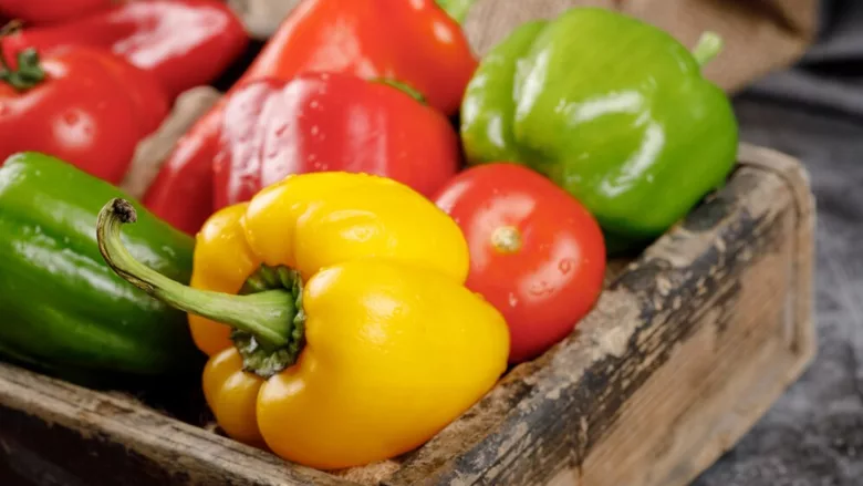 green yellow and red bell peppers in wooden crate