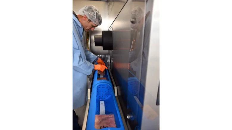 Shade Hughes, FAPC HPP technology manager, loads product into the carrier of the center’s commercial-scale Hiperbaric high pressure processing system