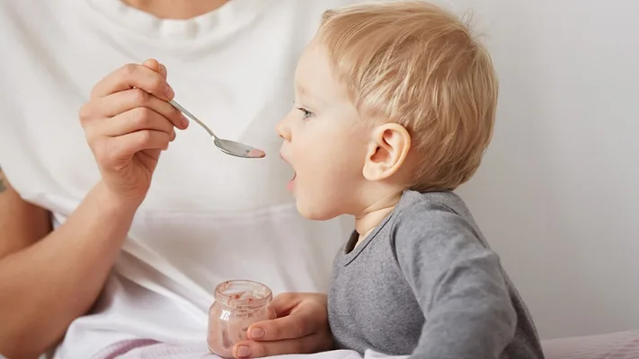 baby being spoon-fed jarred baby food baby being spoon-fed jarred baby food