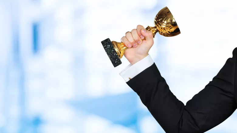 business person's arm holding cup trophy