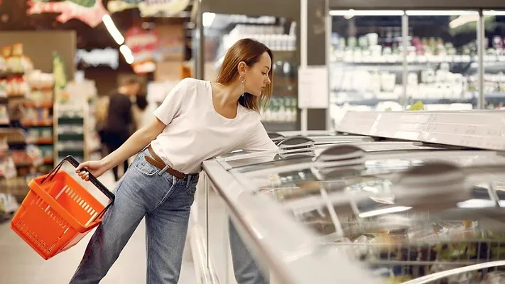 grocery shopper reaching into frozen food cooler grocery shopper reaching into frozen food cooler