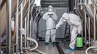 GettyImages-1270395263-Prostock-Studio-iStock-Getty Images Plus.jpg men in hazmat suits cleaning plant