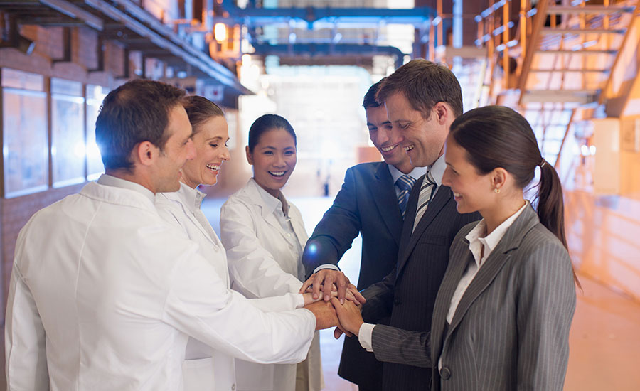 scientists and business people doing team handshake in factory